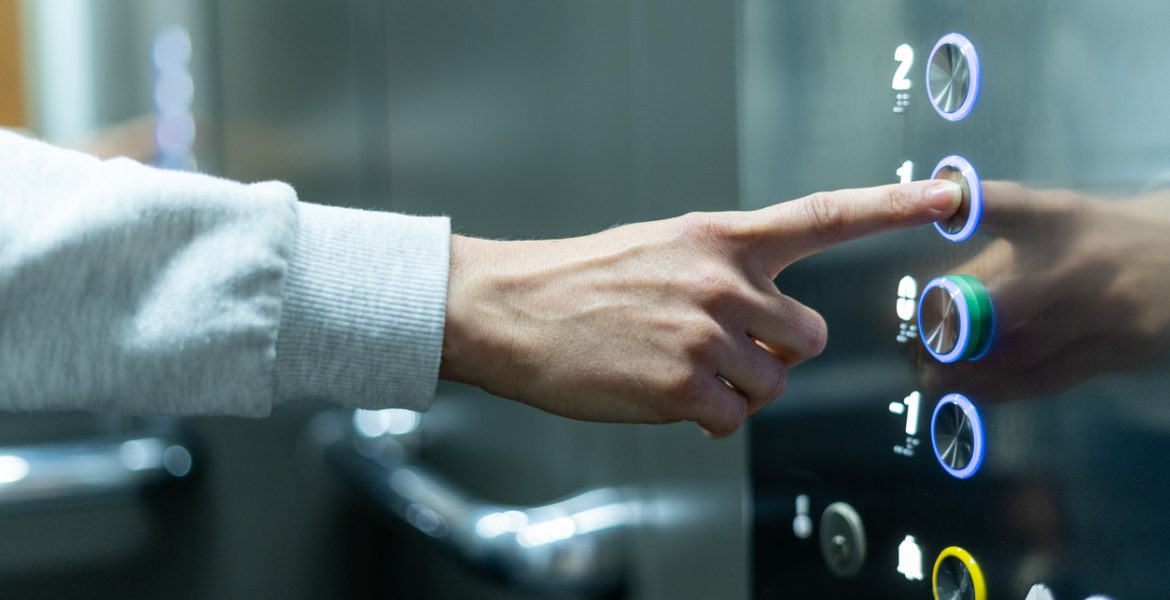 Person selecting first floor being in elevator Closeup of person's hand pushing button to select first floor in elevator. Passenger lift. Businessman in office. Movement within building concept